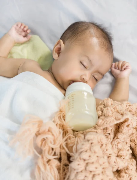 Bebê bebendo leite de garrafa e dormindo na cama — Fotografia de Stock