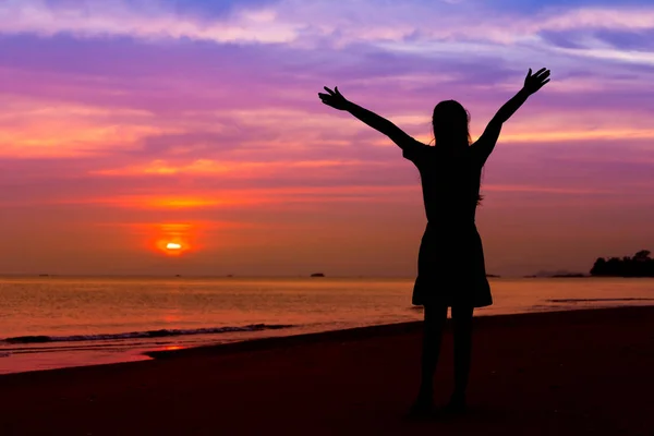 Silhouette of woman with hands up while standing on sea beach at — Stock Photo, Image