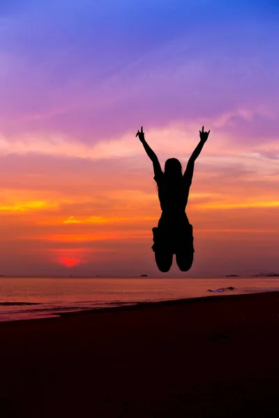 Silhouette of woman jumping with hands up and showing I LOVE YOU sign — Stock Photo, Image
