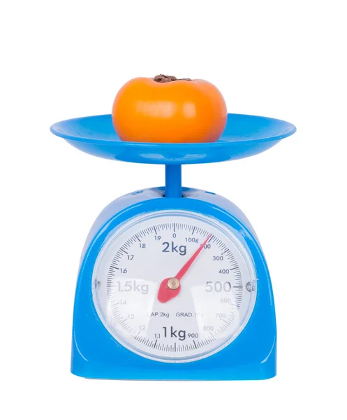 Persimmon on kitchen scale isolated on white background — Stock Photo, Image