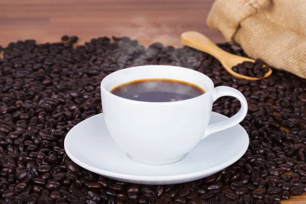 Tasse de café et haricots sur fond en bois — Photo