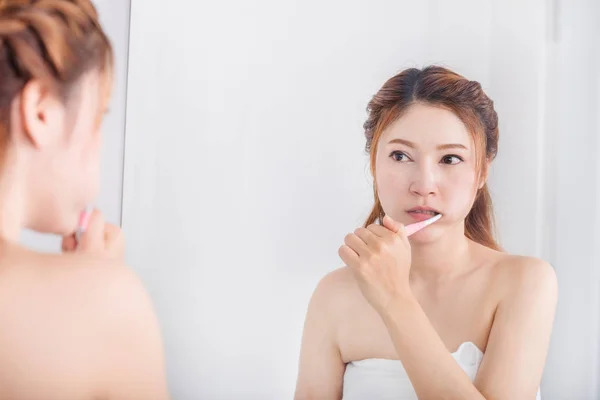 Femme en serviette de bain brossant les dents avec miroir dans la salle de bain — Photo