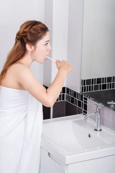 Kobieta w ręcznik szczotkowanie zębów z lustrem w łazience — Zdjęcie stockowe