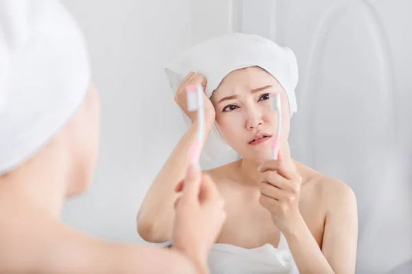 Donna infelice in asciugamano lavarsi i denti con specchio in vasca da bagno — Foto Stock