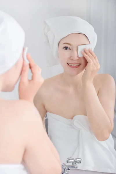 女人看镜子和清洗她的脸与棉花 — 图库照片