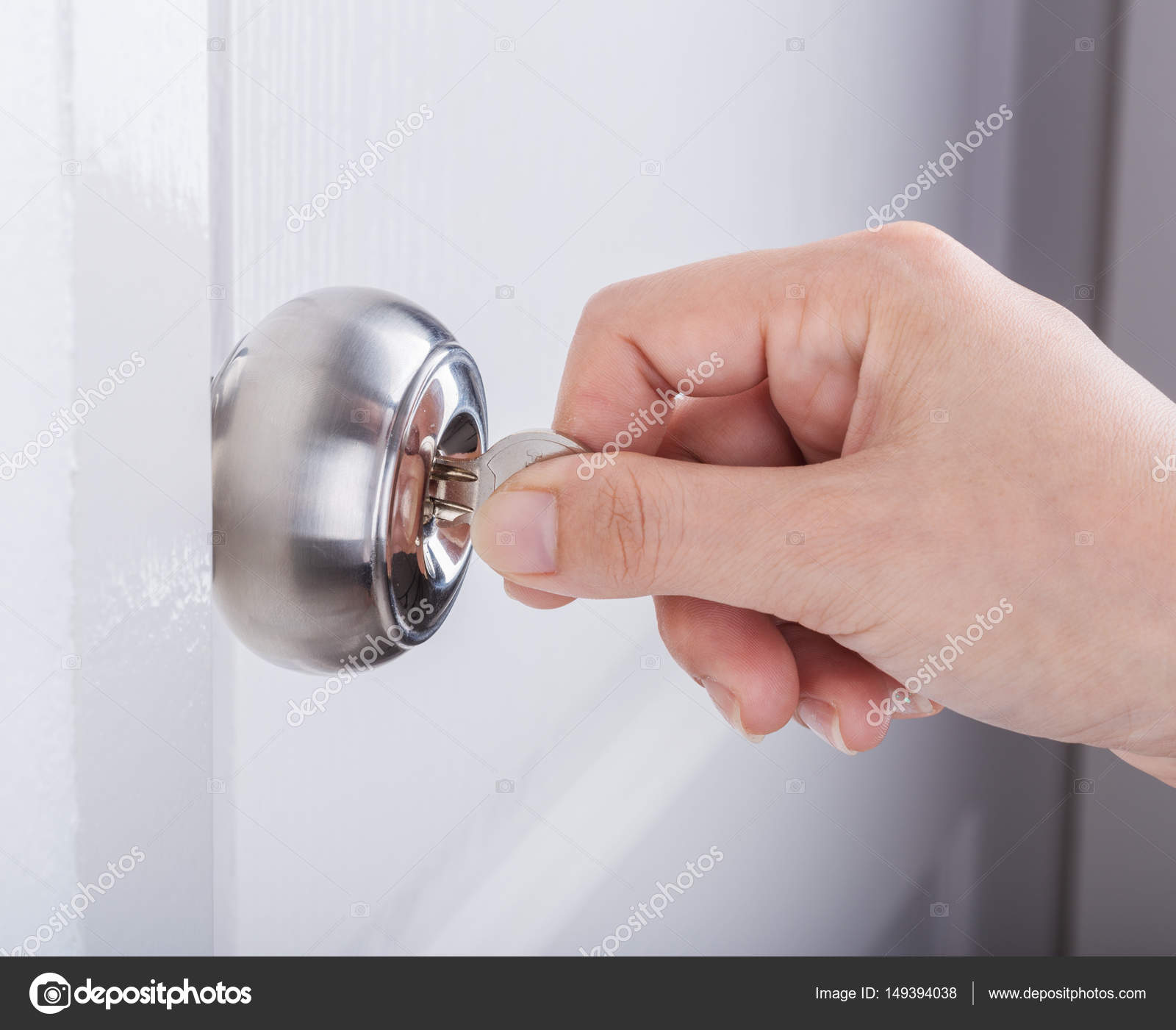 Hand Use The Key For Unlocking Door Knob On White Door