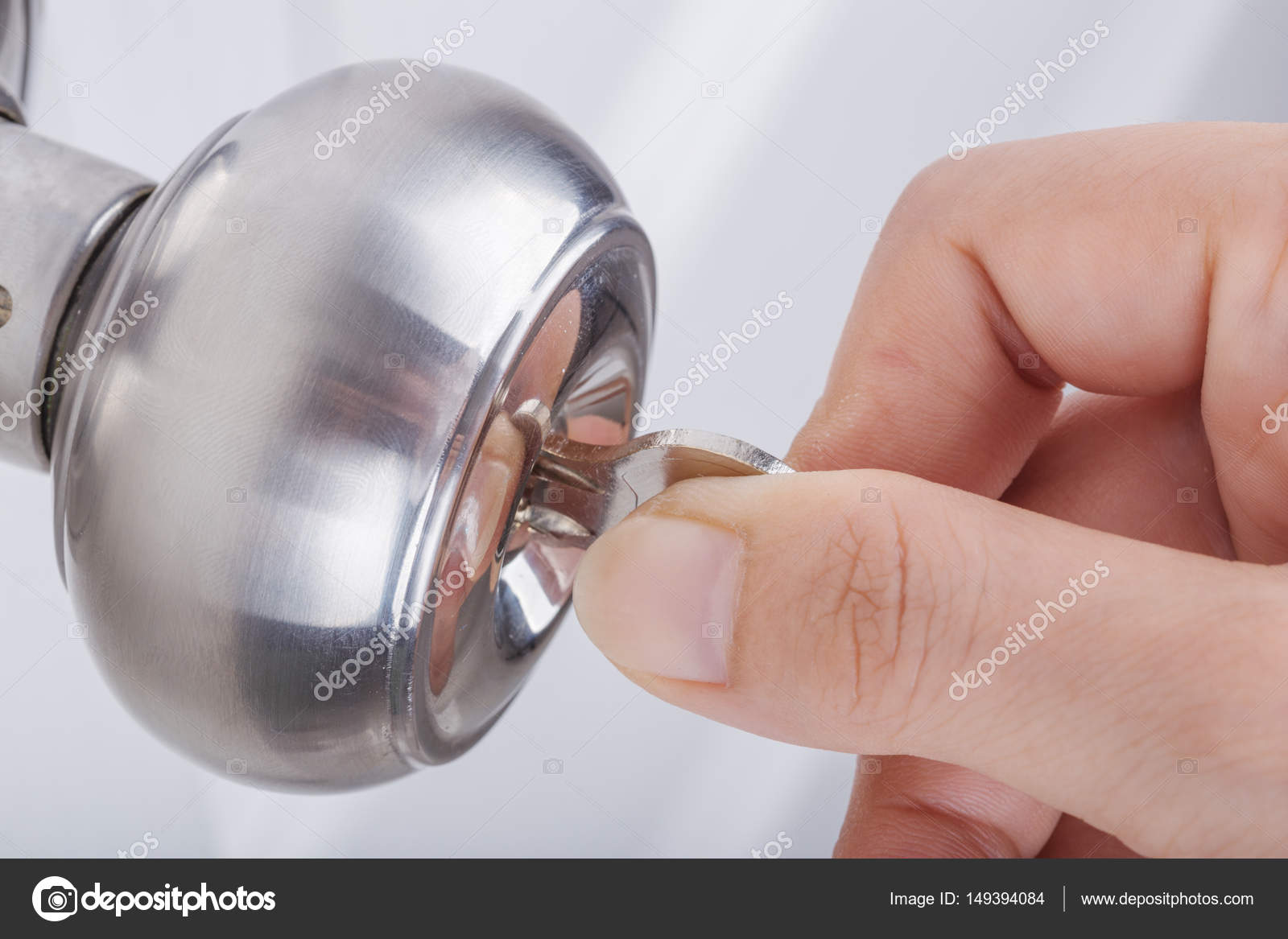Hand Use The Key For Unlocking Door Knob On White Door