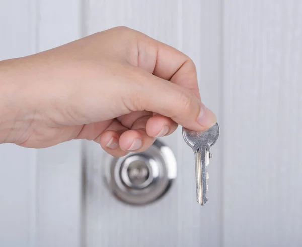 Ключ в руке с фоном дверной ручки — стоковое фото