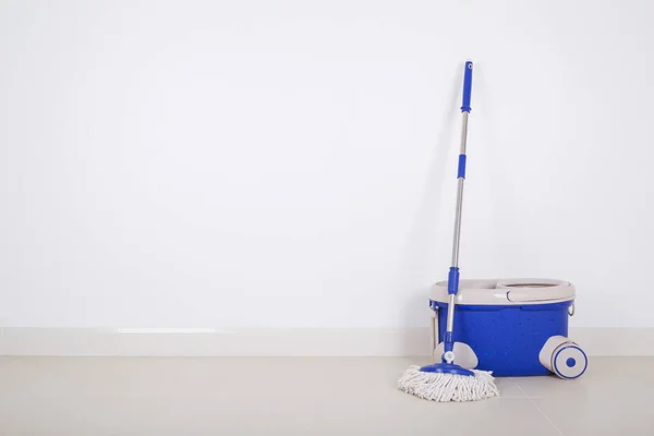 Fregona y cubo azul sobre fondo de piso y pared —  Fotos de Stock