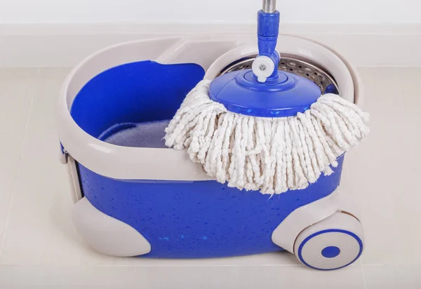 Close-up do esfregão e um balde azul para limpeza do chão — Fotografia de Stock
