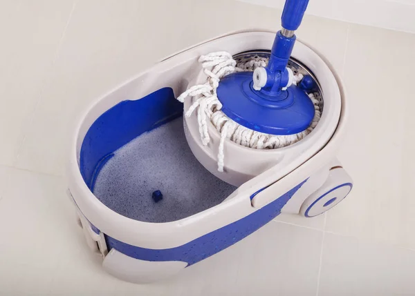 Close-up do esfregão e um balde azul para limpeza do chão — Fotografia de Stock