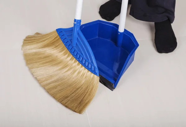 Woman legs with broom and dustpan sweeping floor — Stock Photo, Image