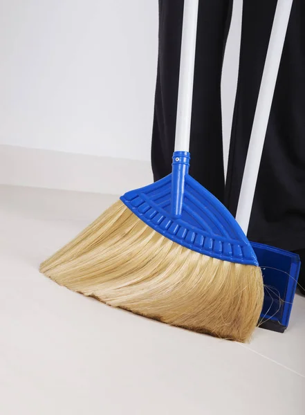 Woman legs with broom and dustpan sweeping floor — Stock Photo, Image