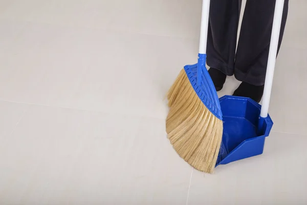 Woman legs with broom and dustpan sweeping floor — Stock Photo, Image