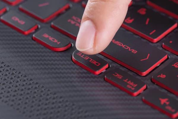 finger pushing delete button on laptop keyboard