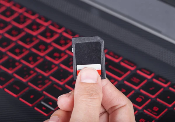 Mão segurando o cartão Sd com laptop — Fotografia de Stock