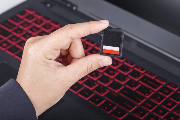 Mão segurando o cartão Sd com laptop — Fotografia de Stock
