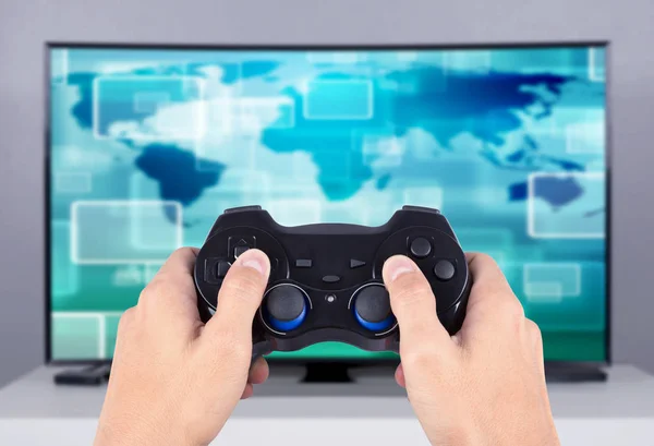 Handen håller joystick till att spela spel på tv — Stockfoto