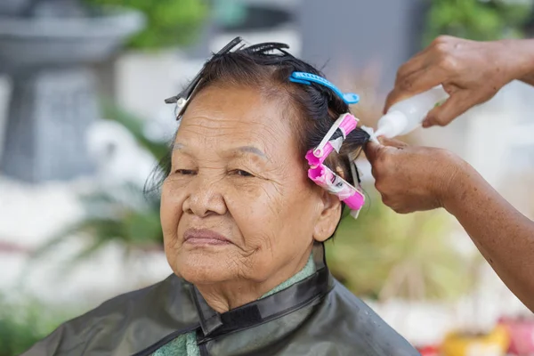 Mâna unui coafeză care face un păr perm de rulare a unei femei în vârstă — Fotografie, imagine de stoc