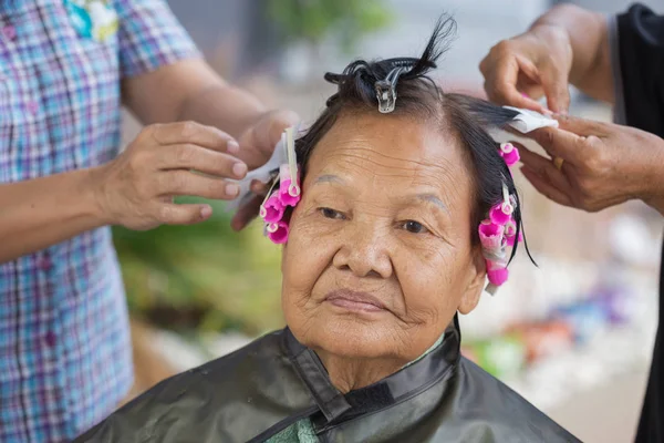 Hand of a hairstylist doing a perm rolling hair of senior woman — Stock Photo, Image