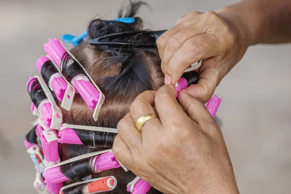 Hand of a hairstylist doing a perm rolling hair of senior woman — Stock Photo, Image