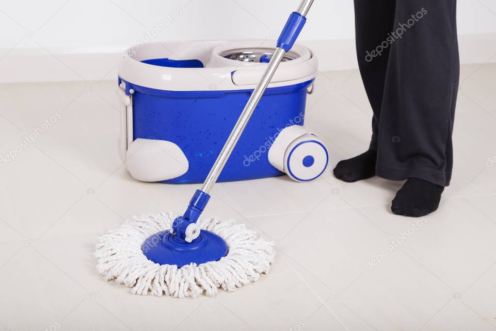 woman legs with mop and bucket cleaning floor