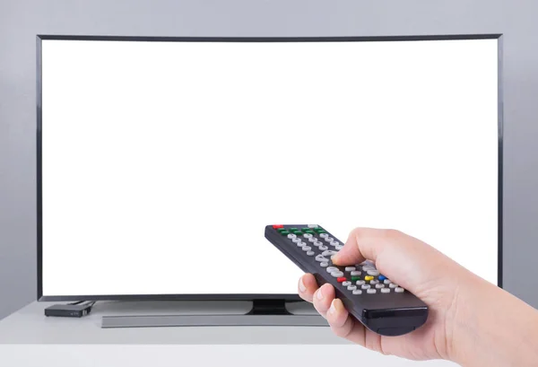 Mano que sostiene el control remoto de la TV con la TV led y la pantalla blanca — Foto de Stock