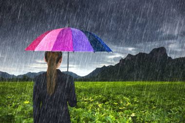 düşen yağmur ile çok renkli şemsiye tutan bir iş kadını