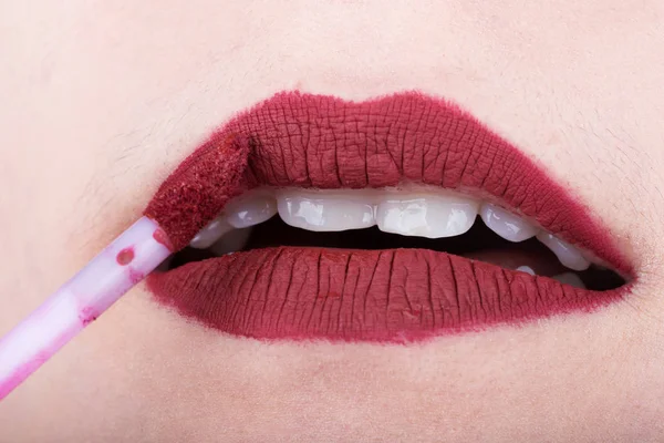 Mulher aplicando batom vermelho em seus lábios — Fotografia de Stock