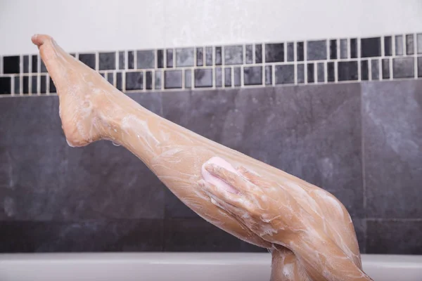 Frau wäscht ihr Bein mit Seife — Stockfoto
