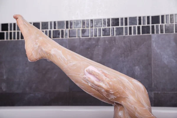 Woman washing her leg with soap — Stock Photo, Image