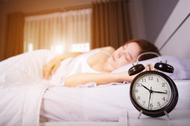 saati 10 am göster. ve güneş ışığı altında mor ile yatakta uyuyan kadın
