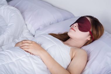 göz maskesi ile yatakta uyuyan kadın