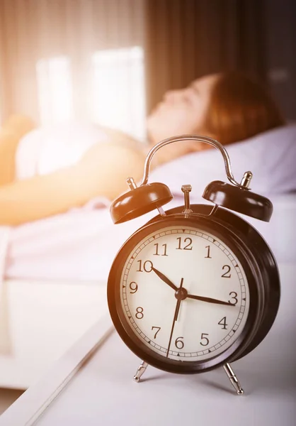 O relógio mostra as 10 da manhã. e mulher dormindo na cama com luz solar no mor — Fotografia de Stock