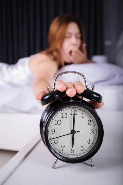 woman sleeping and wake up to turn off the alarm clock in mornin