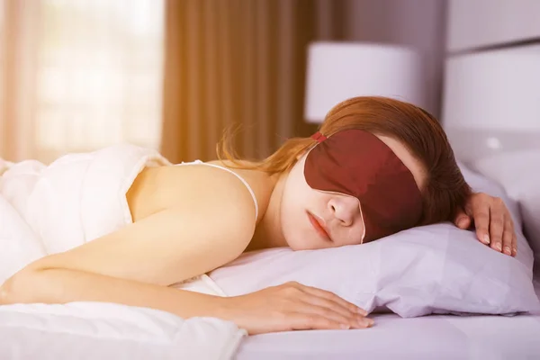 Woman sleeping on bed with eye mask in bedroom with soft light — Stock Photo, Image