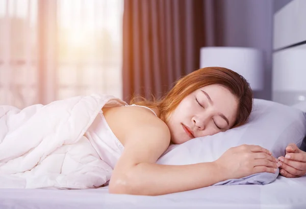 Kvinna som sover på säng med mjukt ljus — Stockfoto