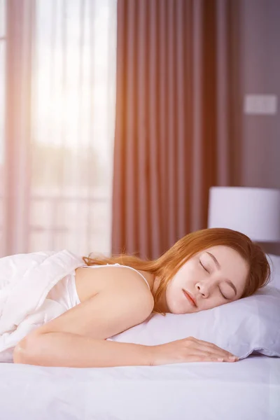 Kvinna som sover på säng med mjukt ljus — Stockfoto