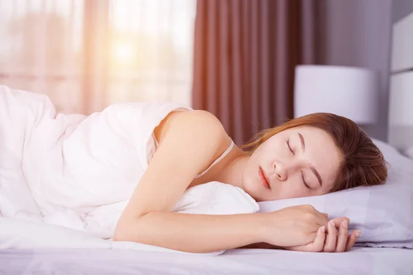 Kvinna som sover på säng med mjukt ljus — Stockfoto