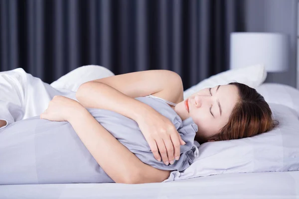 Kvinna som sover med bolster kudde på sängen i sovrummet — Stockfoto