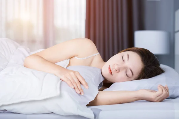 Kvinna som sover på sängen i sovrummet med mjukt ljus — Stockfoto