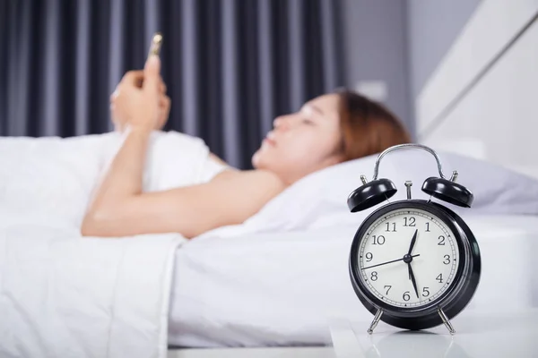 Horloge avec femme en utilisant son smartphone sur le lit — Photo