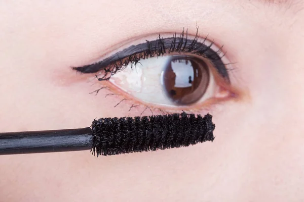 Woman applying mascara on her eyelashes — Stock Photo, Image