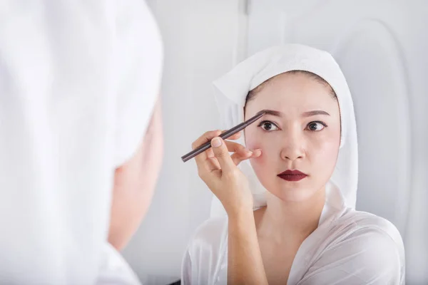 Mulher olhando espelho e usando lápis maquiagem sobrancelha — Fotografia de Stock