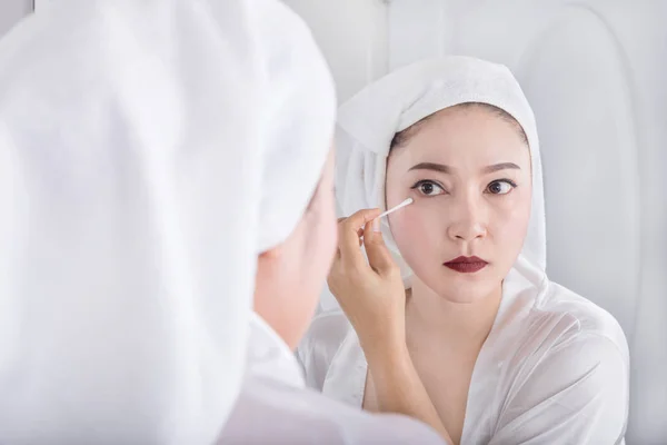 Femme regarder miroir et enlever le maquillage à côté de l'œil avec un coton — Photo