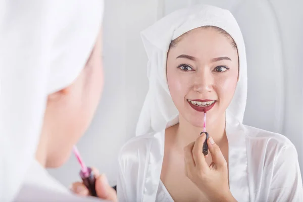 Donna guardando allo specchio e applicando rossetto rosso sulle labbra — Foto Stock