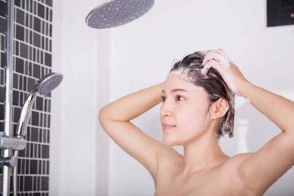 Женщина моет голову и волосы шампунем — стоковое фото