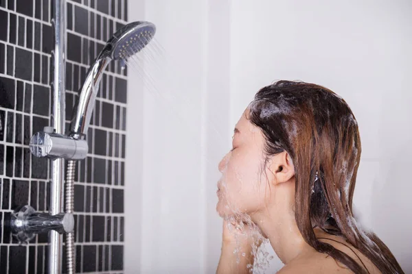 Frau wäscht sich unter der Dusche ihr Gesicht — Stockfoto