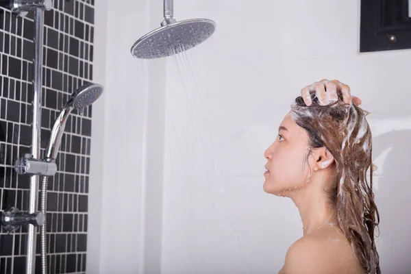 Женщина моет голову и волосы шампунем — стоковое фото