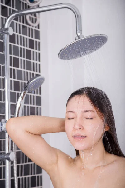 Mulher está lavando seu cabelo e rosto pelo chuveiro de chuva — Fotografia de Stock